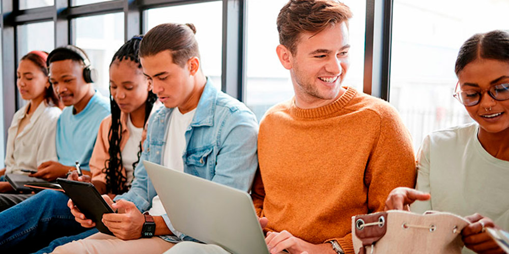 Jóvenes con dispositivos móviles en un centro de Formación Profesional planean qué estudiar según sus intereses: Administración, informática o marketing.